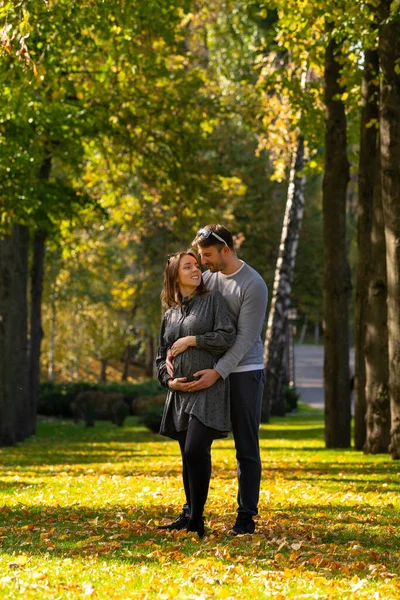 Young couple with pregnant wife standing in a park — Stock Photo, Image