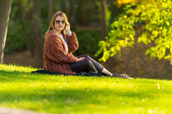 Mulher muito na moda relaxante em um parque de outono — Fotografia de Stock