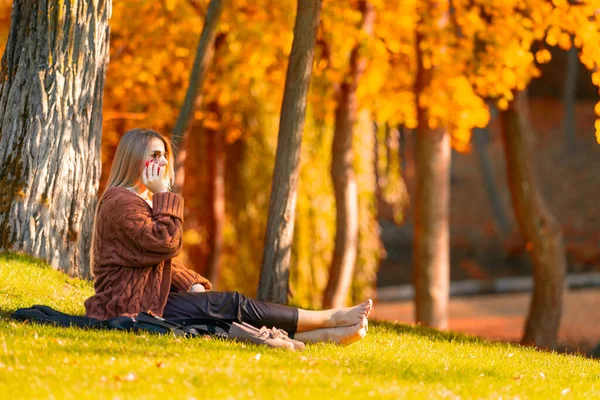 Νεαρή γυναίκα χαλαρώνει ξυπόλητη σε ένα φθινόπωρο πάρκο — Φωτογραφία Αρχείου