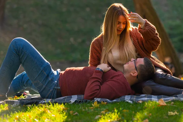 Jovem casal relaxante na grama em um parque — Fotografia de Stock