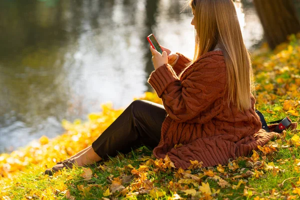 Junge Frau schreibt eine SMS, während sie sich entspannt — Stockfoto