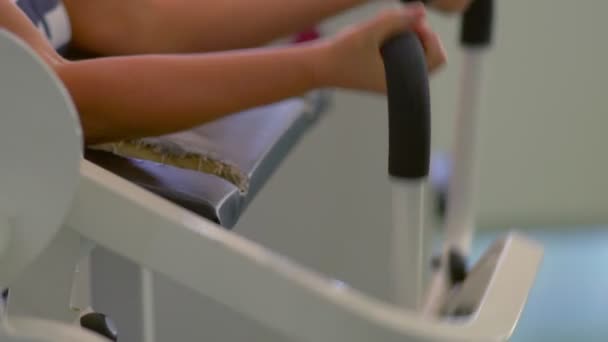 Mujer que utiliza la máquina de entrenamiento en el gimnasio para hacer ejercicio — Vídeo de stock