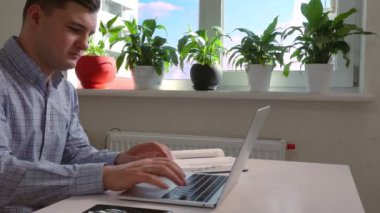 Young businessman typing and taking notes