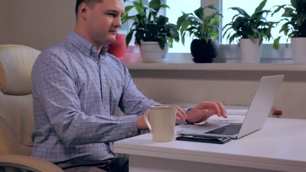 Homme assis à un bureau moderne tapant sur un ordinateur portable — Video