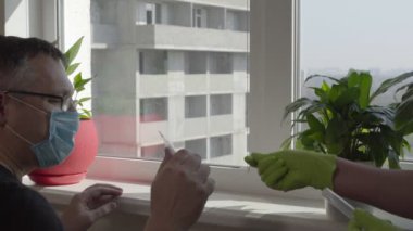 Eldivenli bir adam bir adama termometre uzatıyor.
