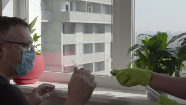 Person in gloves handing a man a thermometer — Stock Video