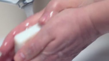 Adam ellerini sabun ve suyla güzelce yıkıyor.