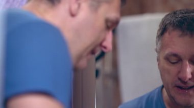 Orta yaşlı bir adam banyoda yüzünü yıkıyor.