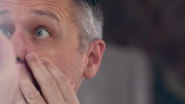 Hombre de mediana edad mirando sus ojos en un espejo — Vídeo de stock