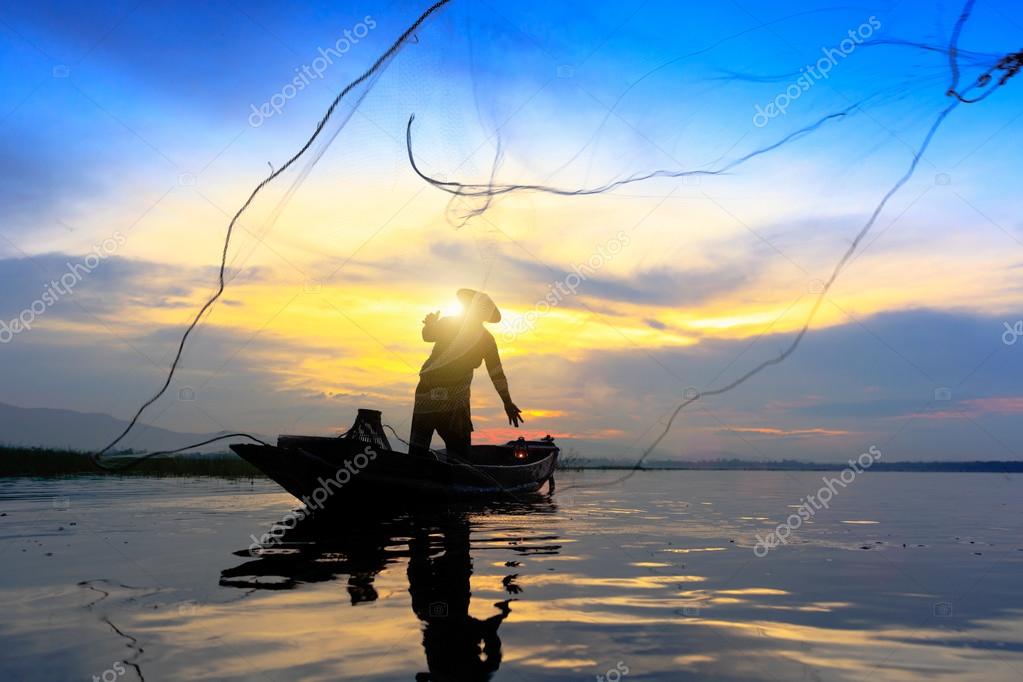 Silhouette fisherman throwing fishing net Stock Photo by