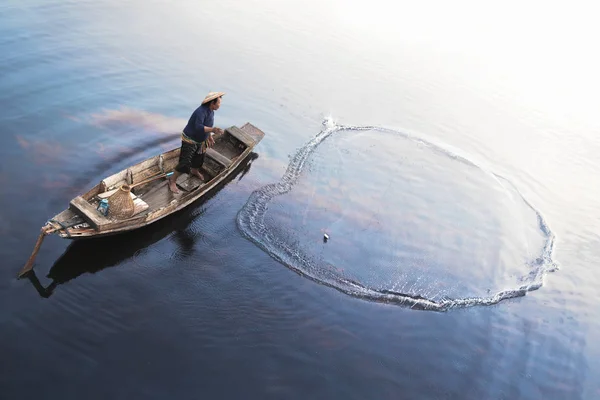 Pescatore asiatico su barca di legno — Foto Stock