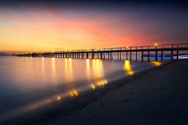 Puente de madera iluminado en una playa — Foto de Stock