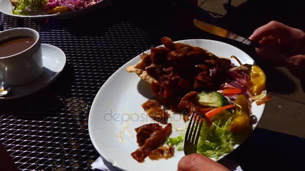 Man eating doner kebab at outdoor cafe — Stock Video