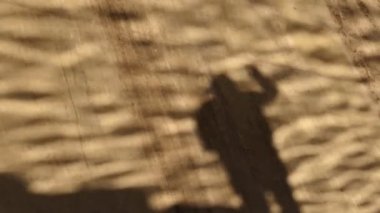 Gölge Adam yavaş dalga yansıma desen zemin dikey bir beton duvar üzerine bir el veda sallıyor. Soyut veda kavramı