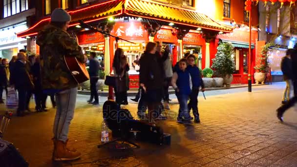英国伦敦 2017年4月 许多人走过去街头音乐家在晚上在唐人街的 Soho 区演奏吉他 — 图库视频影像