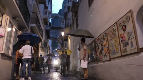 阿马尔菲 意大利 2016年10月 低角度视图意大利沿海城市阿马尔菲 狭窄的大街上的夜景挤满了游客与雨伞 摩托车与车头灯骑在相机 — 图库视频影像