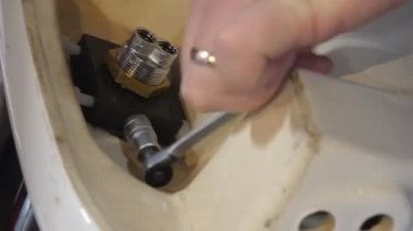 Adamın elleri lavabo kat veya tablo tutarak atış yakın veya ve su Bataryası dokunun ratchet lokma anahtar ve bir anahtar kullanarak sabitleme