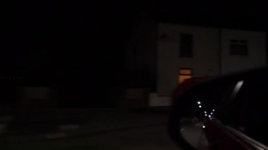 Araba ön yolcu penceresi ve dikiz aynası gece vakti İngiliz kasabasının karanlık caddesine giriyor..