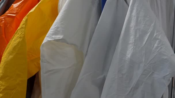 Slow Tilt Showing Protective Bright Colour Clothing Coveralls Hanging Rack — Stock Video
