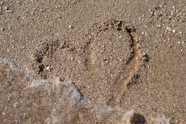 drawing of a heart on the sandy shore of the sea