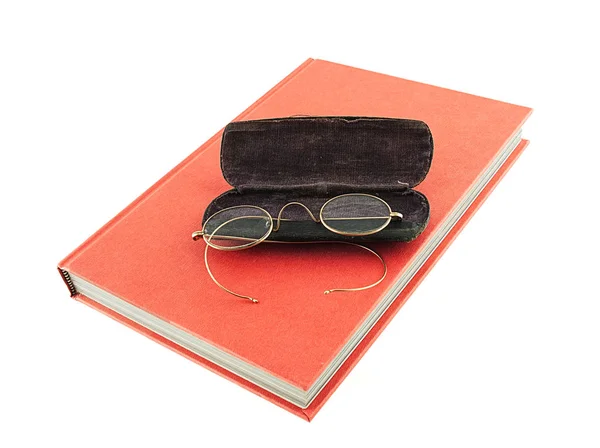 Bir kırmızı bir kitap üzerine oturan eski stil gözlük kapak ve beyaz bir arka plan üzerinde izole
