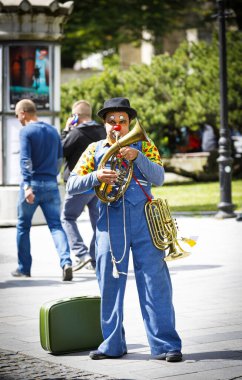Palyaço Tallinn 'de bir sokakta müzik aleti çalıyor.