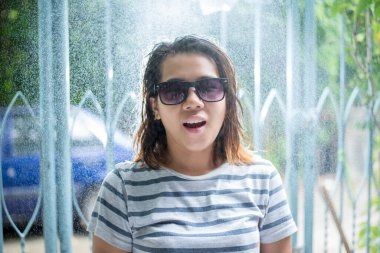 Yağmur yağar, damlalar yüzüne düşer ve kız, çevresindeki hayat ve doğa, doğa ve mutlu hayat kavramı ile mutlu olur.