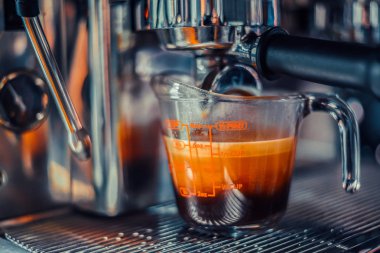 Barista, Americano shot kahve yapıyor, makine de bardağa, yakın plan.