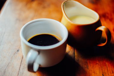Sabahları sıcak kahve ve süt beyaz bardakta masada.