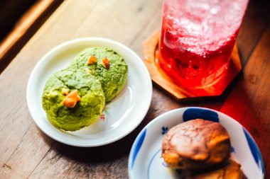 Beyaz çikolatalı kibrit ve çikolatalı brownili kek tabakta kurabiye ve ahşap masada buzlu kırmızı soda..