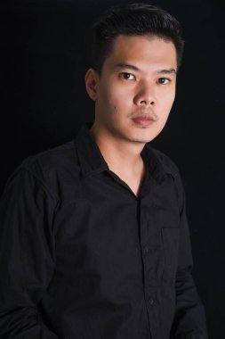 Siyah arka planda siyah gömlekli yakışıklı genç adam, Asya Portresi.