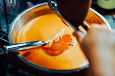 Tahta masa üzerinde süt tenceresi olan Tayland çayı.