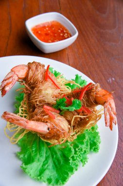 Goong Sarong eriştesi ambalajlı karides gevrek erişte, sebze ve sos ahşap masada beyaz tabak, Tayland yemeği.