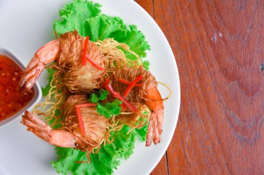 Goong Sarong eriştesi ambalajlı karides gevrek erişte, sebze ve sos ahşap masada beyaz tabak, Tayland yemeği.