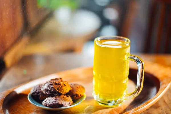 Chinese Chrysanthemum Tea in tall glass and  Brownie cookies on wood table, health herbal tea.