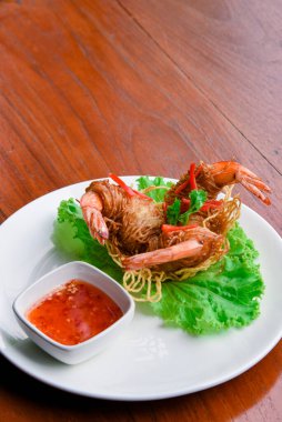 Goong Sarong eriştesi ambalajlı karides gevrek erişte, sebze ve sos ahşap masada beyaz tabak, Tayland yemeği.