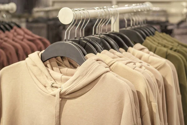Hoodies on hangers in a sports store close-up, clothing concept