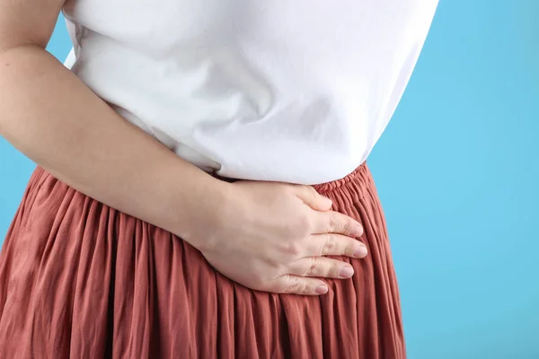穿着白色T恤和裙子抱着肚子的女孩，月经疼痛的概念 — 图库照片