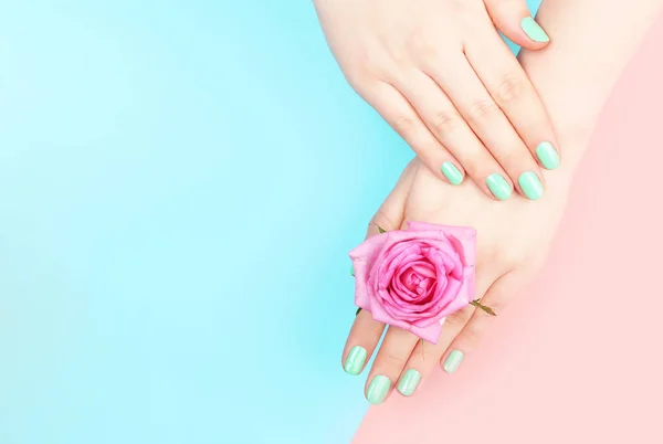 Mãos femininas com manicure cor de hortelã no fundo rosa e azul com espaço de cópia, vista superior — Fotografia de Stock