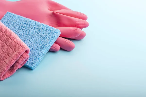 Rag and pink gloves on blue background with copy space.