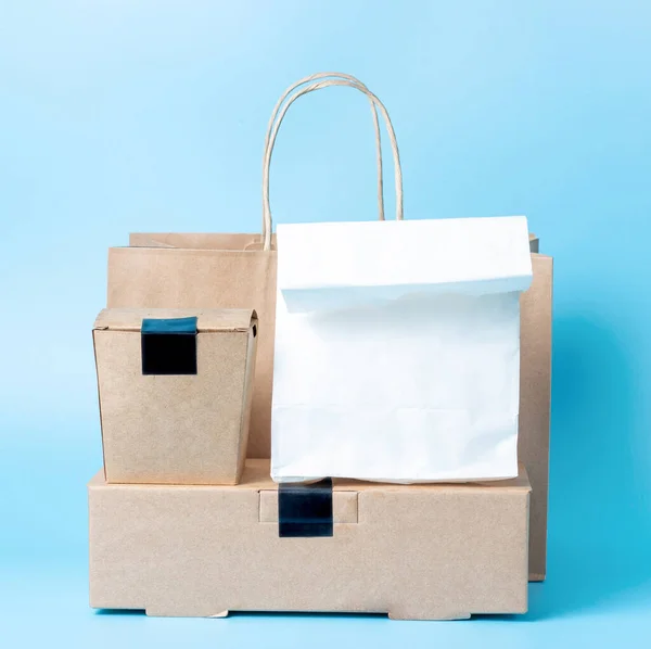 Package and cardboard boxes with food, on a blue background, front view, food delivery concept