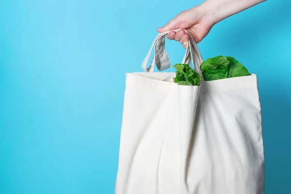 Kvinnans Hand Håller Vit Påse Med Grön Sallad Blå Bakgrund — Stockfoto