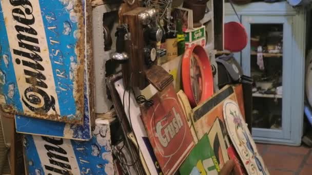 Old tin signs for sale piling up on a flea store in San Telmo Fair. TILT DOWN — Stock Video