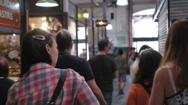 Close-up van een jonge vrouw wandelen tussen toeristen in San Telmo Fair. Dolly binnen. — Stockvideo