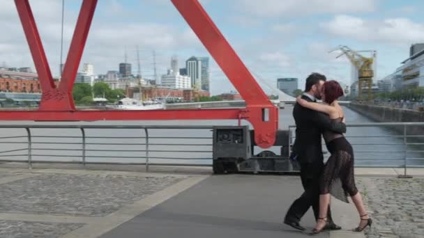 Een paar tango dansers doen coreografie op een brug over Puerto Madero dokken — Stockvideo