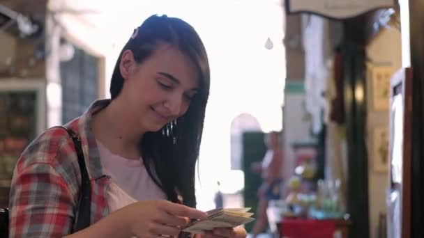 Una joven sonriendo mientras mira artesanías de papel en un mercado — Vídeo de stock