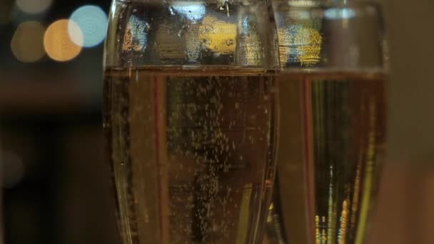 Dos copas de cristal de champán burbujeante sobre un fondo desenfocado — Vídeos de Stock