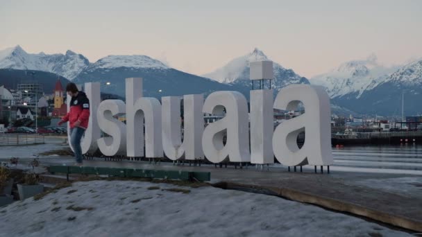 LONG SHOT Tourist taking pictures on Ushuaia sign and mountains on background — Stock Video