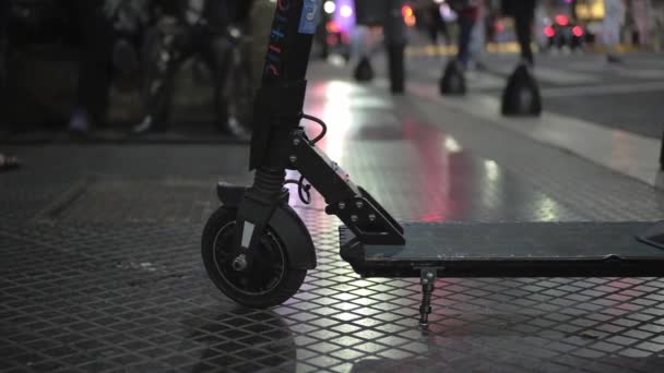 Langzame beweging van een huur elektrische scooter dek en wielen op een drukke stad 's nachts — Stockvideo