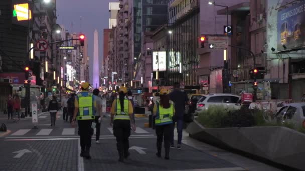 Agentes de tránsito caminando por el lado peatonal de la avenida Corrientes por la noche — Vídeos de Stock